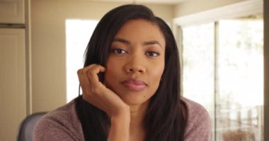 Çenenin altında dinlenen güzel siyah bir kadının portresi. Güzel Afro-Amerikan kadın, nazik gülümsemesiyle kameraya bakıyor. 4k