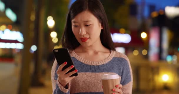 100万人のかわいい女性がスマートフォンでテキストを読み シャンゼリゼパリでコーヒーを飲みながら閉じます フランスでテキストメッセージを読むために携帯電話を使用して快適な若いアジアの女性 — ストック動画
