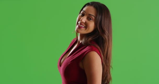 漂亮的拉丁女性穿着性感的红色衣服转身面对着绿色屏幕上的相机微笑 在绿色屏幕上键入或合成 — 图库视频影像