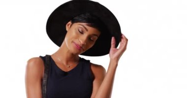 Beyaz arka planda şık Afro-Amerikan kadın modellik yapıyor, gülümsüyor ve gülüyor. Stüdyoda çanta ve diğer aksesuarlarla poz veren zarif bir kadın. 4k