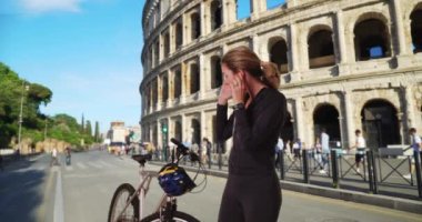 Roma 'da bisiklet sürmeye hazırlanan sağlıklı aktif bir kadın. Bisikletli, kasklı, beyaz bir kadın. 4k