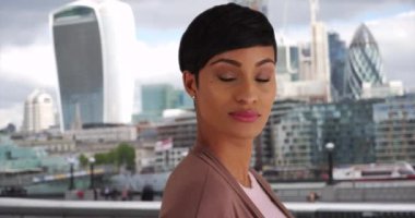 Şehirdeki kendine güvenen iş kadını kameraya gülümsüyor. Londra, İngiltere 'de başarılı bir zenci kadının portresi. 4k