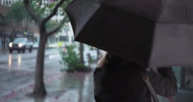 Şemsiyeyle dans eden ve yağmurda gülerek dışarı atlayan tasasız son sınıf öğrencisi kadın. Neşeli yaşlı kadın yağmurlu bir günde dışarıda eğleniyor ıslak kaldırımda şemsiyeyle dönüyor. 4k