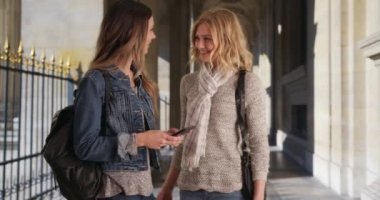 Birkaç kız arkadaş sosyalleşiyor ve güzel, güneşli bir koridorda akıllı telefon kullanıyor. Sarışın arkadaşıyla keşfe çıkarken akıllı telefondan mesaj gönderen iki asyalı kadın. 4k