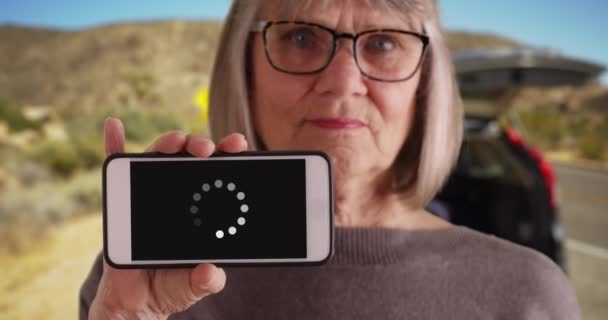Vit Kvinnlig Äldste Visar Laddnings Ikon Telefonskärmen Nära Öknen Motorvägen — Stockvideo