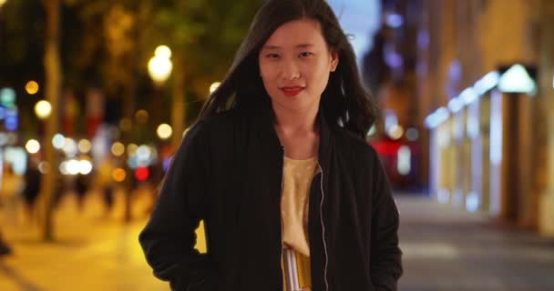 中国人女性黒の爆撃機のジャケットを着て街の通りに夜に立っている ポケットに手を入れてアジア千年紀の女性 — ストック動画