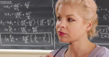 Sınıfta genç ve çekici bir bayan öğretmene yakın durun. Matematik profesörü kameradan dışarı bakıyor, düşünüyor. 4k