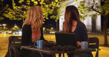 Masada oturan iki çekici kadın Fransa 'nın başkenti Paris' teki Zafer Kemeri 'ne bakıyor. Dizüstü bilgisayar, harita ve kahveyle oturmuş Zafer Yayı 'na bakan iki kız arkadaş. 4k