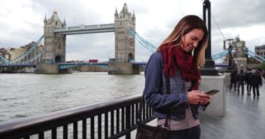 Londralı kadın dışarıda cep telefonuyla mesajlaşıyor. Tower Bridge yakınlarındaki bir kadın cep telefonundan mesaj yolluyor. 4k