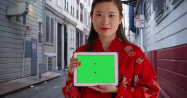 路地のポータブルタブレットから緑の画面を示すかわいい千年紀の女性の肖像画 サンフランシスコの携帯機器に緑色のクロマキーを示す若いアジアの女性のクローズアップカリフォルニア州 — ストック動画
