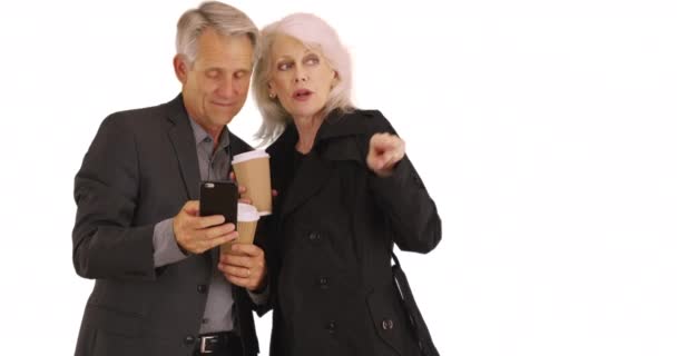 スマートフォンを使用している高齢者は 白い背景に方向を取得します 高齢者のカップルは スマートフォンでGpsを使用してどこにいるかを把握します — ストック動画