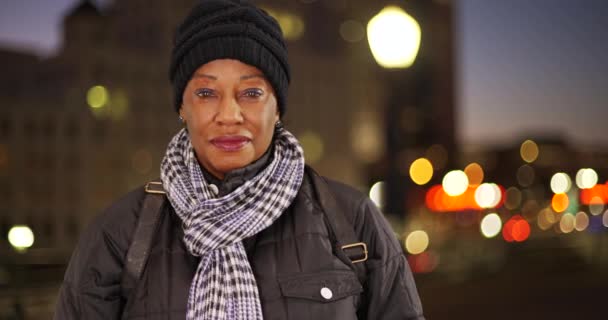 一个穿着保暖衣服的老年黑人妇女在市区的夜晚 一个老年非洲裔美国妇女的肖像在城市的夜晚 — 图库视频影像