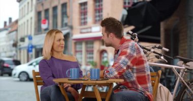 Bruges 'de genç bir çift sohbet ediyor ve kahve içiyor. Çekici erkek ve kadın dışarıda kahve içiyorlar. 4k