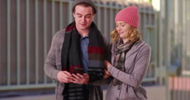 Kışlık giysiler içinde genç bir çift ya da yakın bir arkadaş dışarıda yürüyüş yapıyor, cep telefonuyla gideceği yeri arıyor. Erkek ve kadın kol kola yürüyorlar, GPS için akıllı telefon kullanıyorlar. 4k