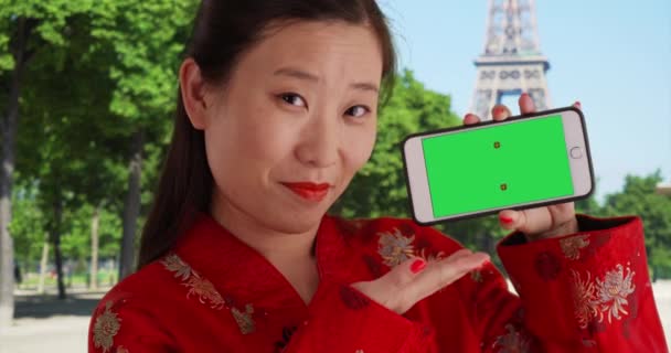 パリフランスのエッフェル塔の前に緑の画面を持つスマートフォンを示す楽しい千年の女性 ヨーロッパの携帯電話から緑のクロマキーを披露素敵な若いアジアの観光客 — ストック動画