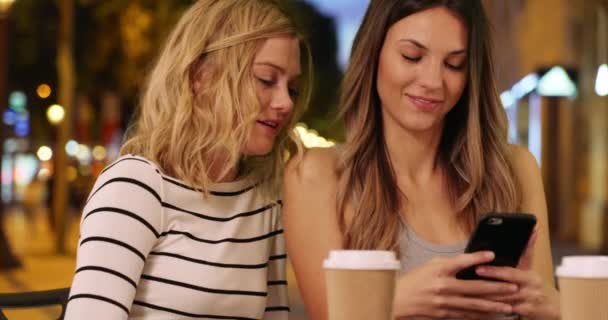 在法国巴黎香客爱丽舍大街的一个漂亮的黑发女人给她的金发朋友看智能手机 两个朋友在欧洲城市共享智能手机的近景 — 图库视频影像