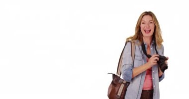 Orta yaşlı beyaz kadın fotoğraf çekiyor ve beyaz arka planda kamerayla konuşuyor. Gülümseyen, elinde kamera olan ve stüdyoda fotokopi çeken neşeli bir kadının portresi..