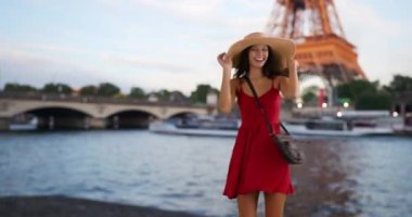 Kırmızı elbiseli kaygısız kadın Paris 'te gülümsüyor ve gülüyor. Eyfel Kulesi yakınlarında mutlu ve çekici bir turistin portresi. 4k