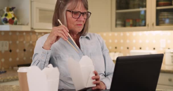 Pensionerad Äldre Kvinna Äter Lunch Och Använder Laptop Dator Hushållsköket — Stockvideo