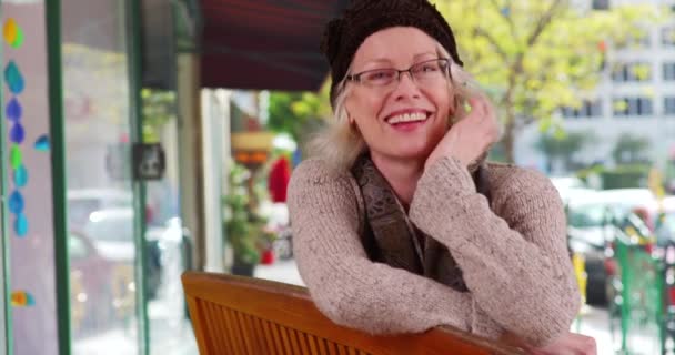 Χαρούμενη Ώριμη Γυναίκα Κάθεται Στον Πάγκο Υπαίθριο Χώρο Χαμογελώντας Στην — Αρχείο Βίντεο