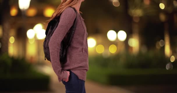 白い千年紀の少女の胴のバックパックを着て 夕方には屋外で誰かを待っているのプロフィール 夜間外に立つ若い白人女性の身体または学生のプロフィール — ストック動画