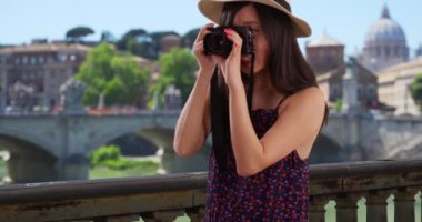 20 'li yaşlarda genç ve mutlu bir bayan turist, İtalya' da Vatikan yakınlarında, DSR kamerasıyla fotoğraf çekiyor. Avrupa 'da fotoğraf çekmek için kamera kullanan bin yıllık fotoğrafçıya yakın çekim. 4k