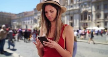 Kırmızı bluzlu şık bir kadın Roma, İtalya 'da telefonla etrafı kolaçan ediyor. 20 'li yaşlarında, Roma' da tatildeyken akıllı telefondan mesaj atan beyaz bir hippi kız. 4k