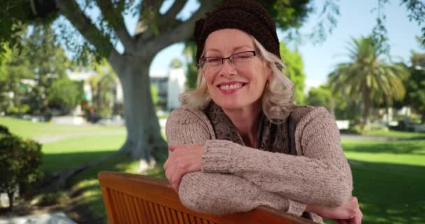 Крупный План Очаровательной Пожилой Женщины Очках Сидящей Скамейке Парке Улыбающейся — стоковое видео