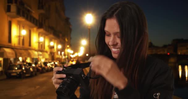 イタリアの爆撃機のジャケットのヒップスターの女の子のクローズアップは アーノ川によって夜の都市部の通りにいる間に写真を撮る フィレンツェでの休暇中の百万人の女性は 夜にカメラで写真を撮る — ストック動画