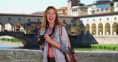 Seyahat fotoğrafçısı Ponte Vecchio Köprüsü 'nün fotoğraflarını çekiyor. Floransa 'da kameraya konuşan kadın turistin portresi. 4k