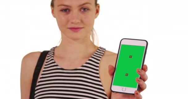 孤立した背景に緑の画面を示すスマートフォンを保持素敵な千年紀の女の子 コピースペースの電話から緑のクロマキーを共有する美しい若い女性 — ストック動画