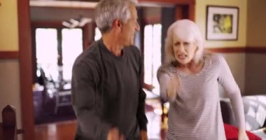 Aktif kıdemli çift oturma odasında dans ediyor. Sağlıklı yaşlılar dans ediyor ve evde ter döküyorlar. 4k