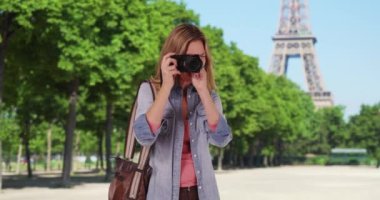 Paris 'te seyahat fotoğrafçısı dışarıda gülümserken fotoğraf çekiyor. Paris 'te yaz tatilinin fotoğrafını çeken bir kadın turist. 4k
