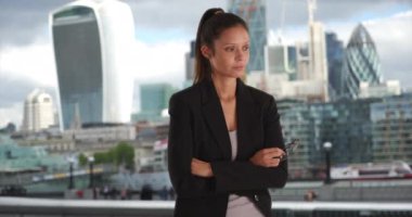 Milenyum iş kadını, siyah spor ceketli, açık havada kollarını açarken, arkasında Londra Skyline ile. Thames 'in yanında genç bir profesyonelin gözlüklü portresi. 4k