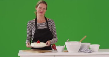 Neşeli beyaz kadın yeşil ekranda pasta tatmaya çalışıyor. Anahtar ya da birleşik olmak üzere yeşil ekranda.