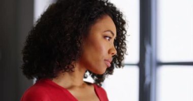Düşüncelere dalmış genç bir zenci kadın kapalı mekan ortamında kameraya doğru dönüyor. Sıradan Afro-Amerikan milenyum kızı binanın içindeki kameraya doğru dönüyor. 4k