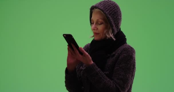 迷人的老年女性穿着毛衣在绿色屏幕上的手机短信 快乐的老年妇女发短信给绿色屏幕上的某个人 让他们进行键入或合成 — 图库视频影像