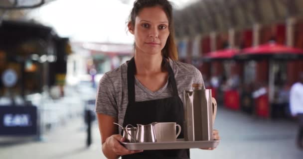 不快乐的女服务员在外面端着盘子里的咖啡和茶 严肃而有魅力的女人穿着围裙 提着托盘端饮料的肖像 — 图库视频影像