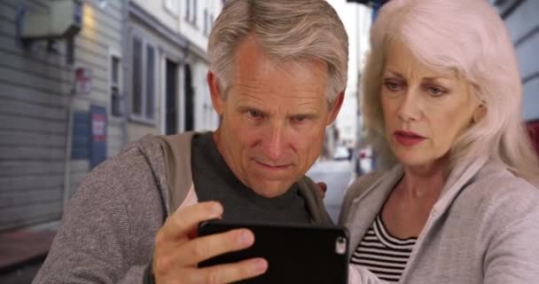 スマートフォンを使用しているシニアカップルは 方向を取り戻す スマートフォンでどこにいるかを把握しようとする高齢者を混乱させました — ストック動画