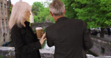 Bruges 'de selfie çeken tatlı olgun bir çift. Yaşlı erkek ve kadın cep telefonuyla fotoğraf çekiyorlar. 4k