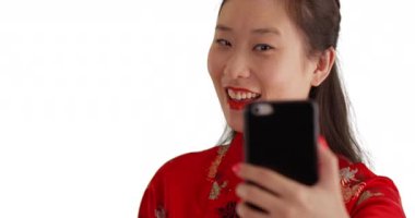 Mutlu milenyum kadınlarının selfie çekerken gülümsemeleri ve beyaz arka planda geleneksel Çin modası giymeleri. Genç gülümseyen Asyalı kadın fotokopi çekmek için akıllı telefon kullanıyor. 4k