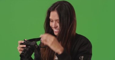 DSR kamerasıyla yeşil ekranın önünde fotoğraf çeken kadın fotoğrafçının portresi. Yeşil ekranda fotoğraf çekmek için dijital kameraya odaklanan yaratıcı kadına yaklaş. 4k
