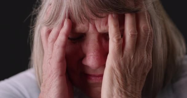 在灰蒙蒙的背景下 紧张的老年女性面对着痛苦 老年妇女偏头痛在灰色背景下揉搓头的特写镜头 — 图库视频影像