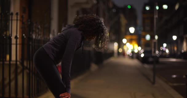 夜市内の黒人女性アスリートがジョギングから休憩している 街中で活発な服装をした女性ジョガーが息をしている — ストック動画
