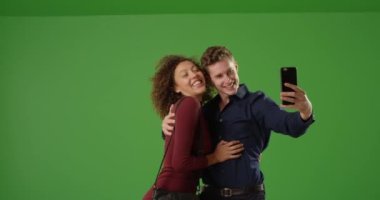 Yeşil ekranda cep telefonuyla selfie çeken sevimli bir çift. Anahtar ya da birleşik olmak üzere yeşil ekranda.