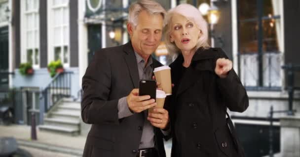 スマートフォンを使用してスマート高齢者が家に帰る方法を見つける 現代の高齢者のカップルの方向性を取得する技術を使用して — ストック動画