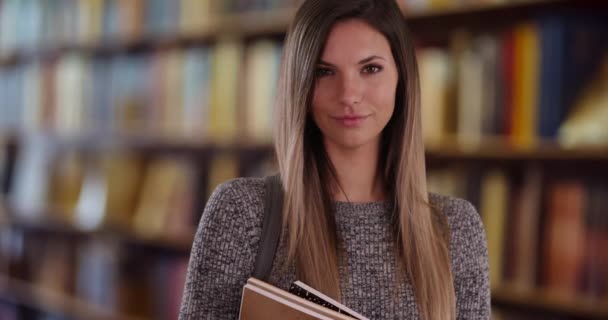 有信心的千禧年女学生在安静的图书馆里看书 在大学里聪明的年轻白人女性在书架上摆姿势的画像 — 图库视频影像