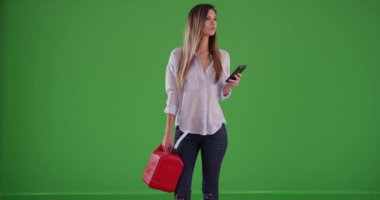 Kırmızı benzin bidonu tutan yolda kalmış kadın sürücü yeşil ekranda cep telefonundan yardım arıyor. Milenyum kadınının benzini ya da benzini bitti ve cep telefonu kullanarak yakıta ihtiyacı var. Yeşil arkaplanda 4k