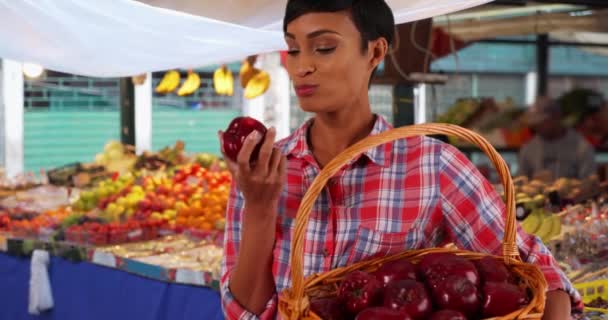 笑容满面的年轻黑人女人咬着多汁的苹果 在农贸市场上 健康迷人的女性正在吃新鲜的有机水果 — 图库视频影像