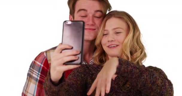 这对快乐的年轻夫妇在白色背景下与智能手机合影 并配上了版权 恋人在带复制空间的工作室里用手机自拍的合影 — 图库视频影像